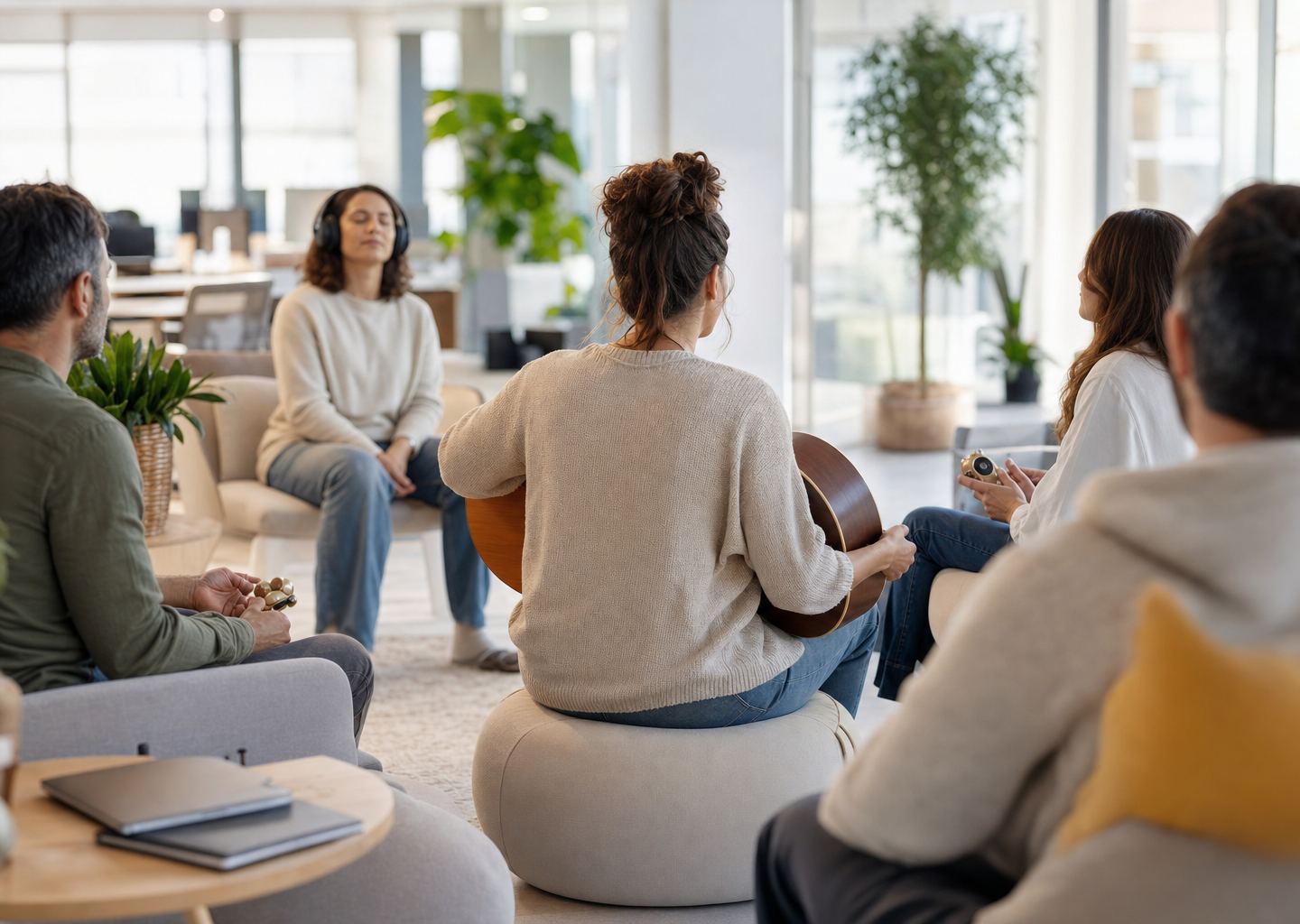 Atelier de musicothérapie en entreprise : salariés détendus en cercle avec un musicothérapeute dans un open-space lumineux